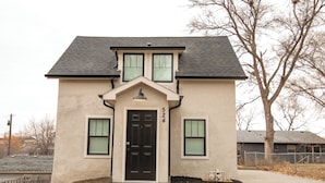 A two-story house with a black front door, a small porch, and a mailbox.