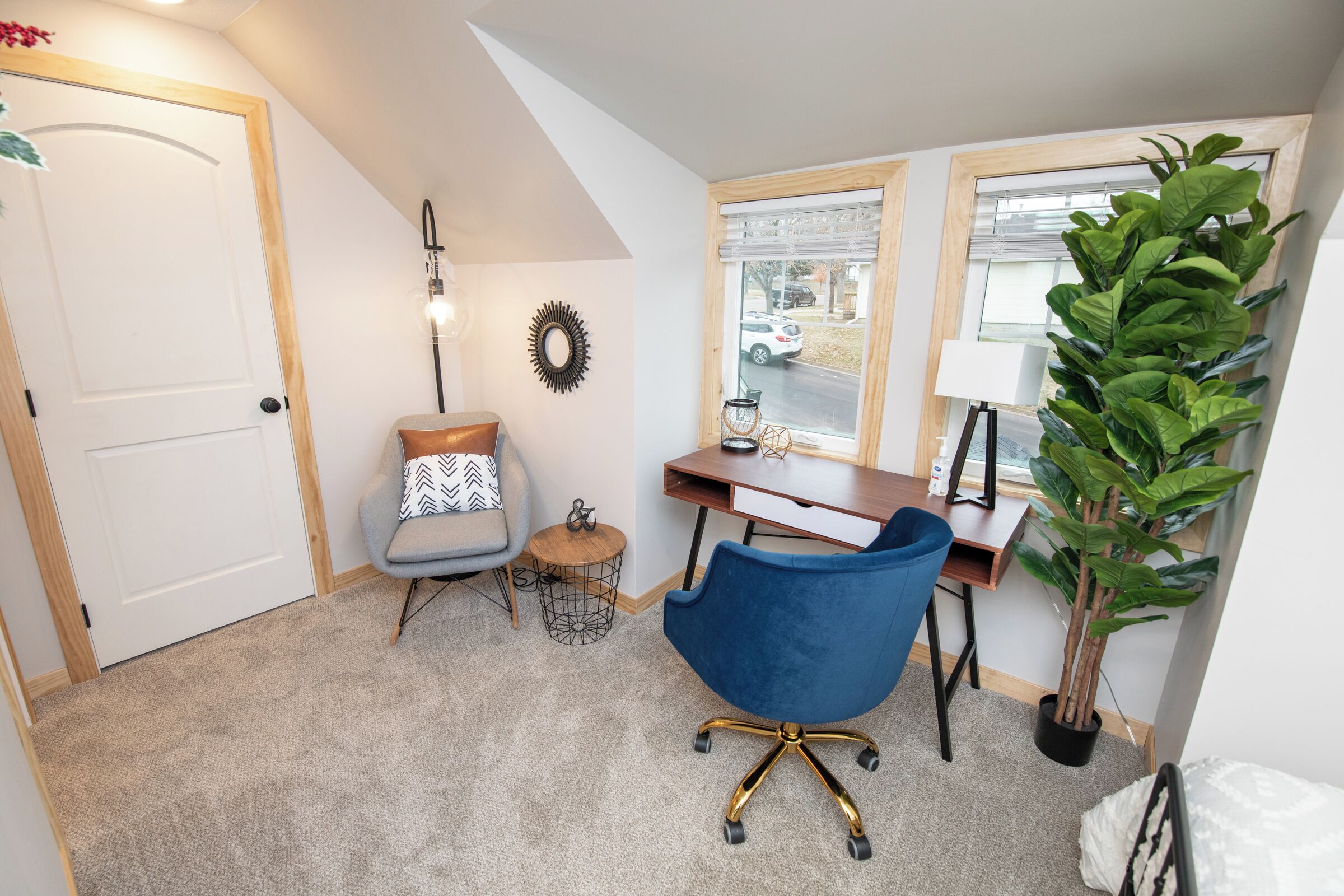 Una habitación con escritorio, silla, lámpara y planta en maceta.