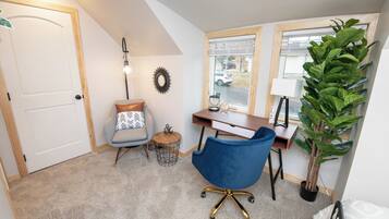 Una habitación con escritorio, silla, lámpara y planta en maceta.