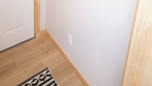 A white door with a modern lock, a welcome sign with hooks, and a patterned rug on a wooden floor.