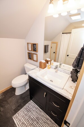 Une salle de bain moderne avec des toilettes blanches, un meuble-lavabo à deux vasques et un grand miroir.