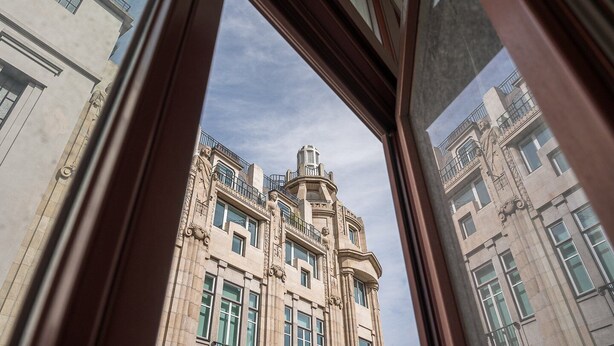 A view through a window of a building with classical architecture, featuring multiple stories, large windows, and decorative elements. - GuestReady - Downtown City Apartments - 2F (Porto)
