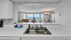 Una cocina moderna con una isla grande, un lavamanos doble y vistas al océano.
