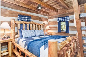 A log cabin bedroom with a wooden bed frame, checkered curtains, and a quilted blanket.