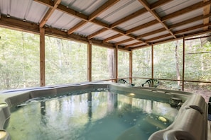 Un jacuzzi bajo un techo de madera con vistas a árboles.