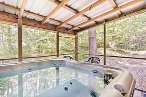 A hot tub in a wooden structure with a view of a forest.