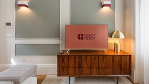 Zona de recepción de hotel con una consola de madera, un letrero que dice 'GUEST READY' y dos lámparas fijadas a la pared.