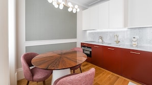 Una cocina moderna con una mesa redonda de madera, armarios rojos y una encimera blanca.
