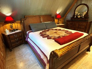 A bedroom with a wooden bed, a quilt, two nightstands with lamps, a dresser, and a mirror.