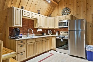 A kitchen with wooden cabinets, stainless steel appliances, and a red-tiled backsplash.