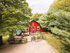A red barn with a green roof, surrounded by trees and a gravel path. - Woodland view-Hitchin' Post (Laurelville)