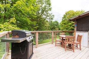 A wooden deck with a grill, a table, and chairs.