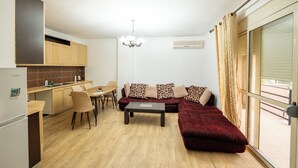 A compact living space with a kitchenette, a dining area, a sofa, and a large window.