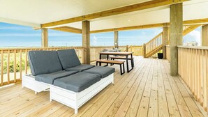 Eine überdachte Terrasse mit einer weißen Couch und einem Tisch mit Stühlen.