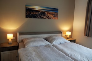 A neatly made double bed with two bedside tables, each with a lamp, in a hotel room. - Stunning beachfront vacation apartment with a fireplace, in a quiet location   (Dranske)