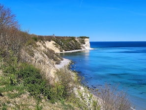Un paisaje costero con acantilados, vegetación y un mar azul cristalino.