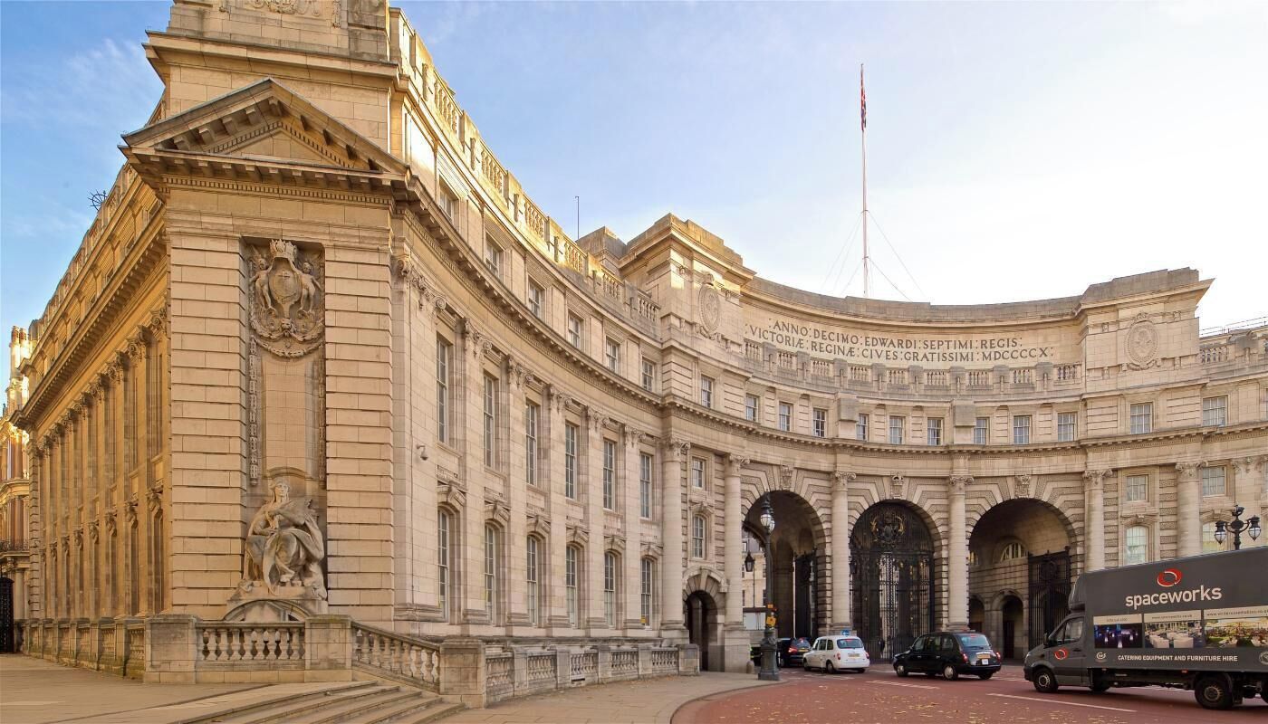 A historic building with classical architecture, featuring a large arched entrance and a statue on the facade.