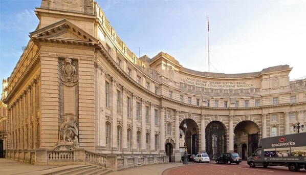 A historic building with classical architecture, featuring a large arched entrance and a statue on the facade.