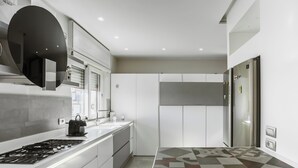 A modern kitchen with a gas stove, white cabinets, and a patterned countertop. - I Ludovici Luxury B&B (Casoria)