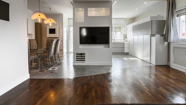 A modern living room with a flat-screen TV, wooden flooring, and a dining area with chairs and a table. - I Ludovici Luxury B&B (Casoria)