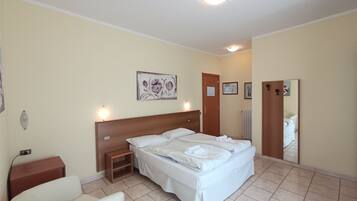 Ein Hotelzimmer mit Bett, Nachttisch, Sessel und Spiegel.