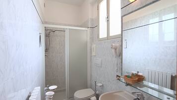 Un baño moderno con cabina de ducha de vidrio, inodoro, lavabo con repisa de vidrio y espejo.