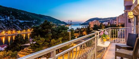 A balcony with a view of a body of water, a bridge, and surrounding buildings.
