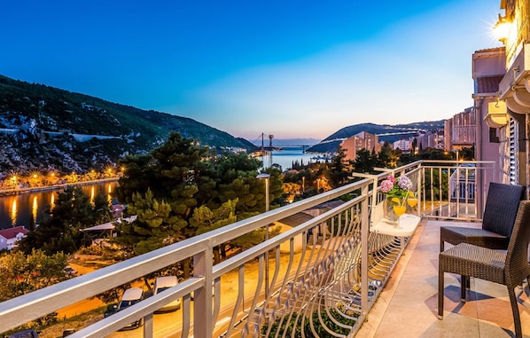 A balcony with a view of a body of water, a bridge, and surrounding buildings.