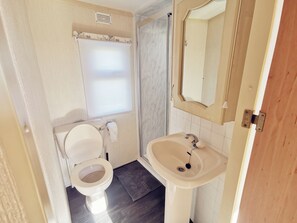 A compact bathroom with a toilet, sink, and shower. - Plum 3 Coral Beach Ingoldmells 2 bed 6 Berth (Skegness)
