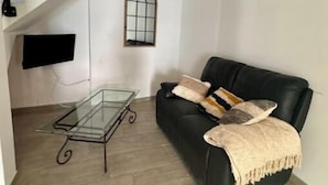A modern living room with a glass coffee table, a black leather sofa, and a staircase leading to an upper level. - La Maison de Sainte-Eulalie (Roubia)
