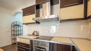Una cocina moderna con extractor de acero inoxidable, horno empotrado y una encimera con hervidor.