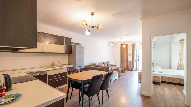 Una cocina moderna con comedor, piso de madera y una lámpara en el techo.
