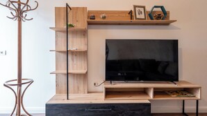 Una sala de estar moderna con una unidad de almacenamiento de madera, un televisor de pantalla plana y un perchero.