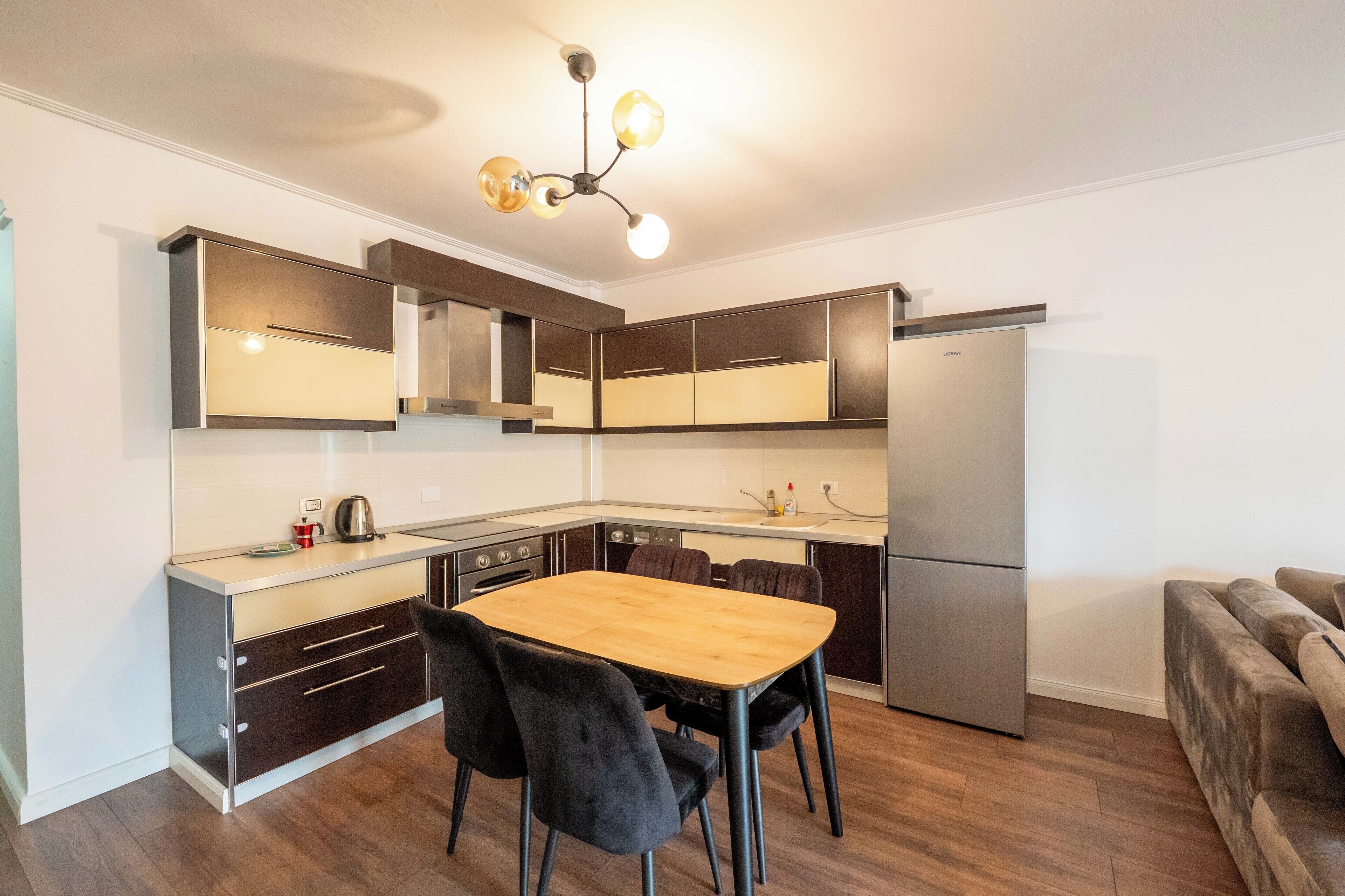 A modern kitchen with dark cabinetry, a wooden dining table, and a built-in oven.