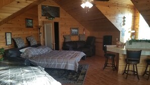 Une chambre mansardée chaleureuse, avec un lit, une chaise, un bureau et un ventilateur de plafond.