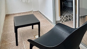 A room with a hammock, a black chair, and a small table. There is a door leading to a bathroom with a toilet and a patterned floor. - Treeloft 29 (Girón)