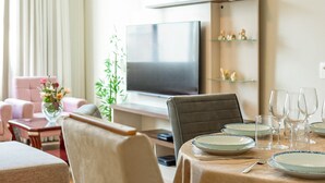 Un coin repas avec une table dressée pour quatre personnes, un téléviseur au-dessus et une plante sur le côté gauche.