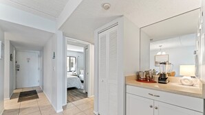 A modern bathroom with a large mirror, a countertop with a blender, and a shower area.