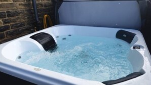 A hot tub with water jets, set against a brick wall.