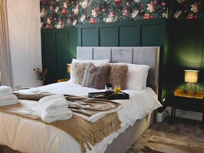 A neatly made bed with a fluffy blanket, pillows, and a tray with a glass of orange juice.