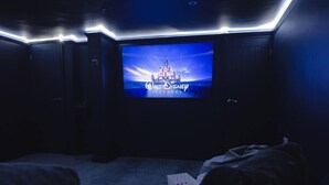 A darkened room with a large screen displaying the Walt Disney Pictures logo, indicating a movie theater setting.