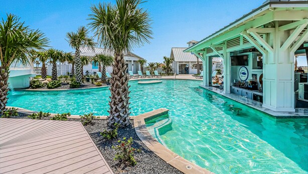 Una piscina con zona de bar, palmeras y un área de descanso cubierta.