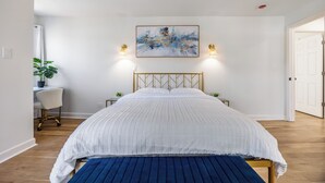 A bedroom with a large bed, a desk with a chair, a potted plant, and two wall-mounted lights. - Near Ravinia and Navy Base, charming 3-bedroom house in peaceful Highland Park (Highland Park)