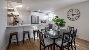 A modern kitchen with white cabinets, a stainless steel refrigerator, and a large island with stools. - Near Ravinia and Navy Base, charming 3-bedroom house in peaceful Highland Park (Highland Park)