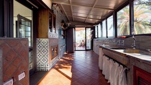 A kitchen with a tiled floor, wooden cabinets, and a large window with a view of palm trees. - The Prince's "Casena" - Historic home with a sea view (Palermo)