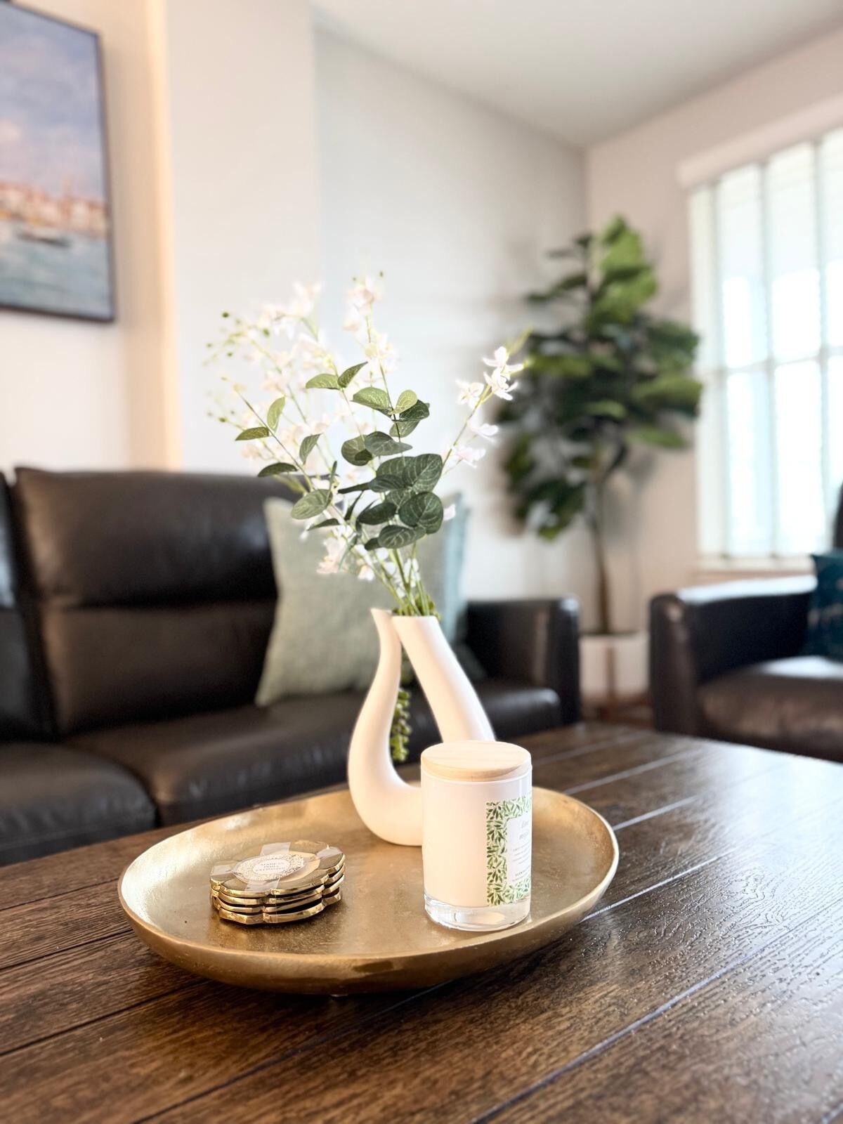 Una bandeja de madera con una vela y un florero de flores sobre una mesa.