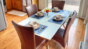 A dining area with a table set for four, surrounded by wooden chairs, a chandelier, and a view of the backyard through glass doors. - The Cozy Corner, 2-bedroom townhome in charming Newark with WiFi, and parking (Newark)
