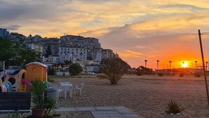 A beach with a sunset, a playground, and buildings in the background.