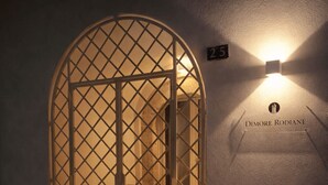 A window with a lattice design, a wall-mounted light, and three lanterns on a ledge.