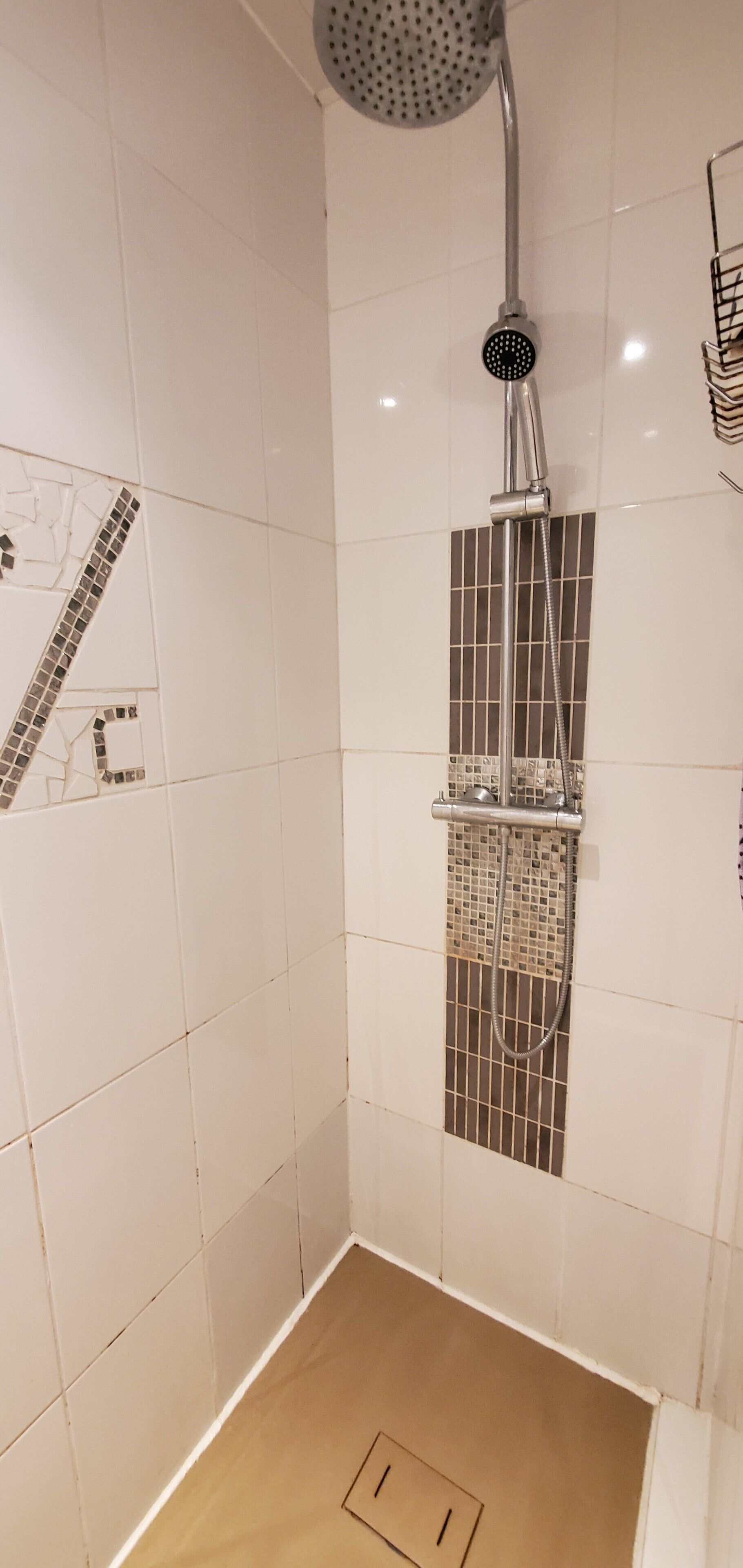 Une douche équipée d’un pommeau de douche à main et d’un panneau de commande fixé au mur.